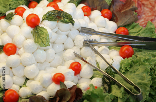 tray of white mozzarelline, red cherry tomatoes and green lettuc photo