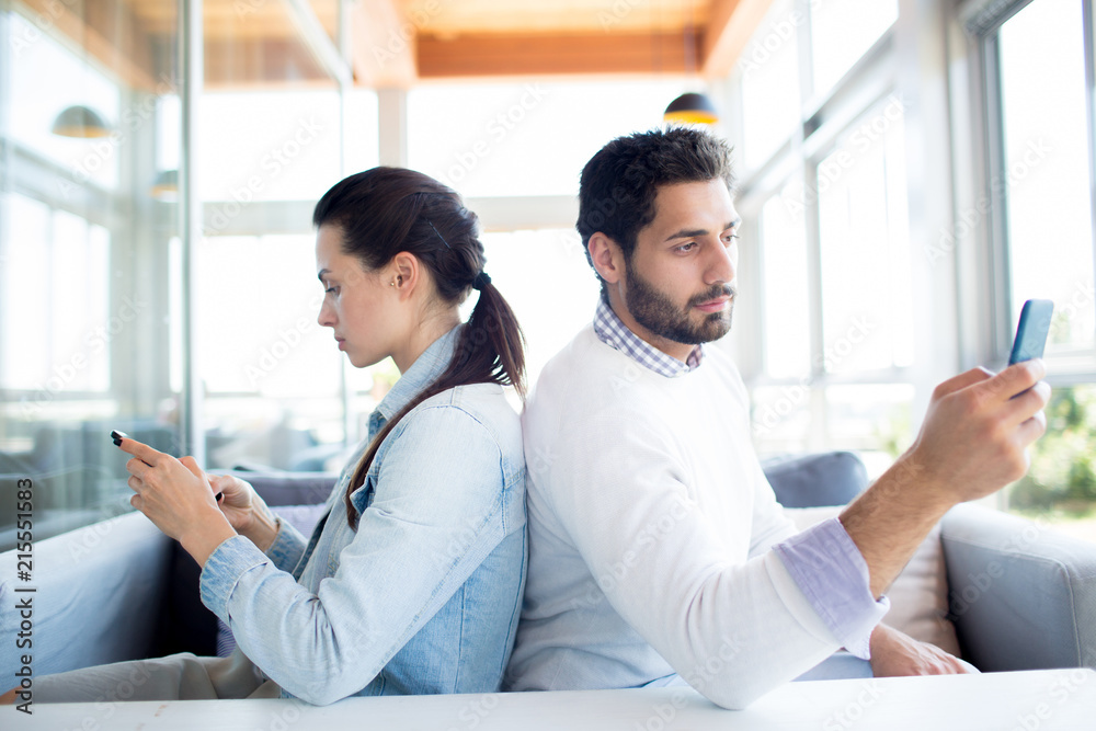Ταπετσαρία Young casual man and woman sitting back to back in cafe and communicating in the