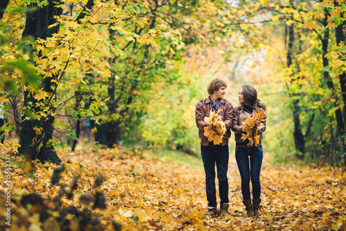 Loving happy couple in autumn in park holding autumn maple leaves in hands. © Marina Varnava