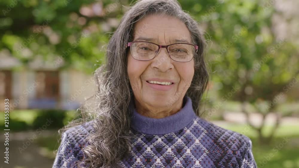portrait of pretty elderly indian woman smiling happy looking at camera in garden background portrait of pretty elderly indian woman smiling happy looking at camera in garden background