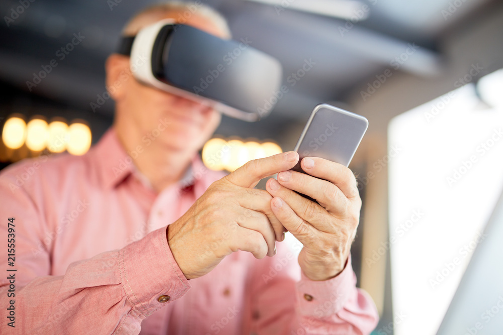 Fototapeta premium Senior businessman in vr headset using his smartphone while watching webcast