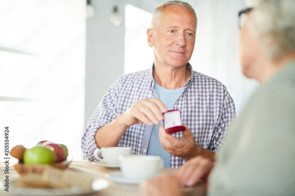 Fototapeta premium Aged man giving his wife new ring for family occasion or for her birthday while having tea
