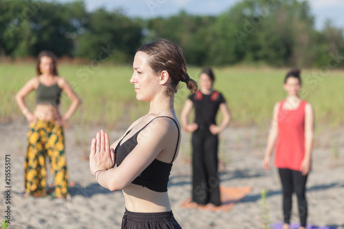 Fototapeta Naklejka Na Ścianę i Meble -  yoga teacher and students practicing yoga outdoors