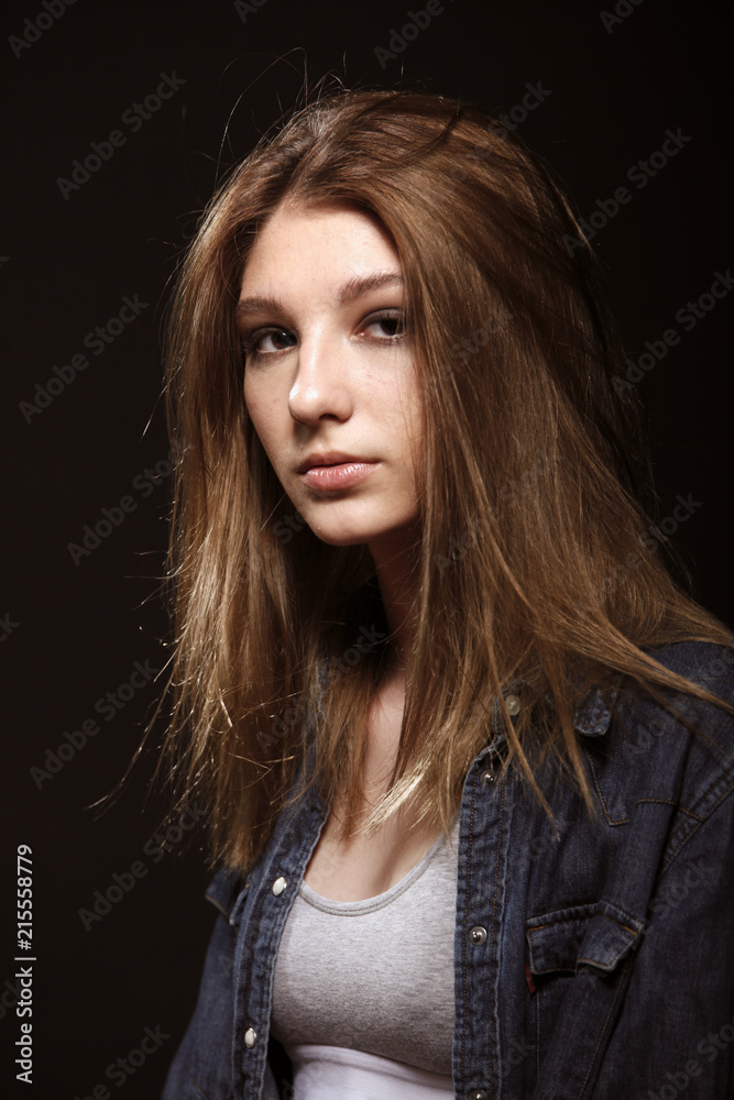 one teenage girl, long hair, beautiful fashion model posing, looking away. studio, black background.