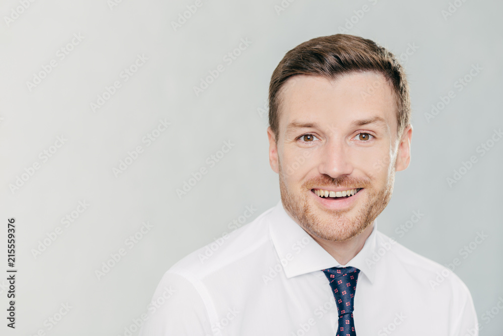 Studio shot of handsome unshaven male entrepreneur with cheerful expression, rejoices raising sales, dressed in formal clothes, isolated over white background with copy space aside for your text Studio shot of handsome unshaven male entrepreneur with cheerful expression, rejoices raising sales, dressed in formal clothes, isolated over white background with copy space aside for your text
