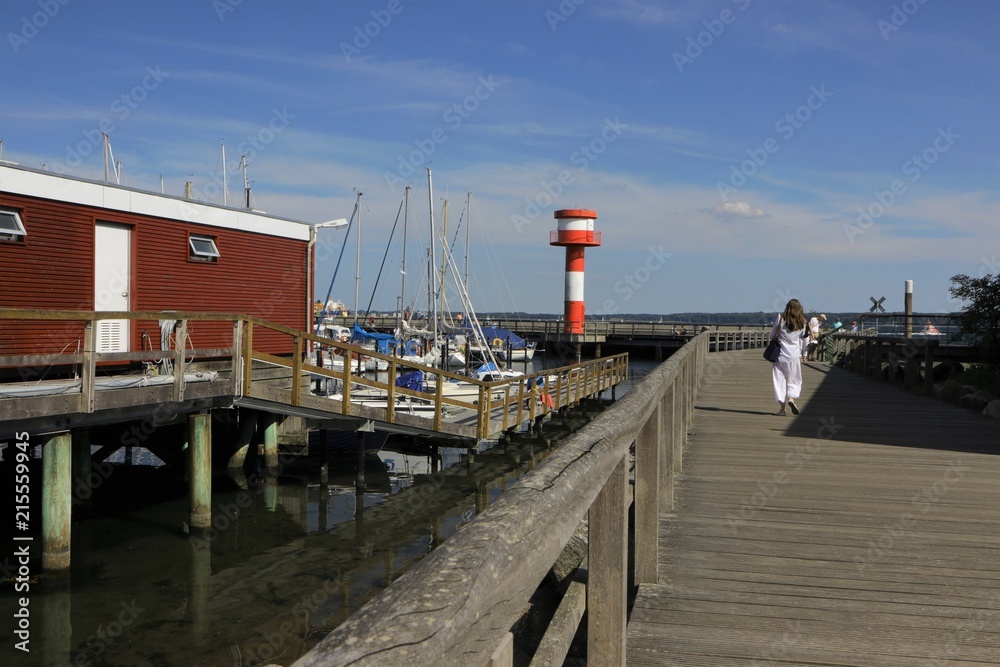 Frau geht spazieren am Hafen vom beliebten Urlaubsort Eckernförde im Sommer