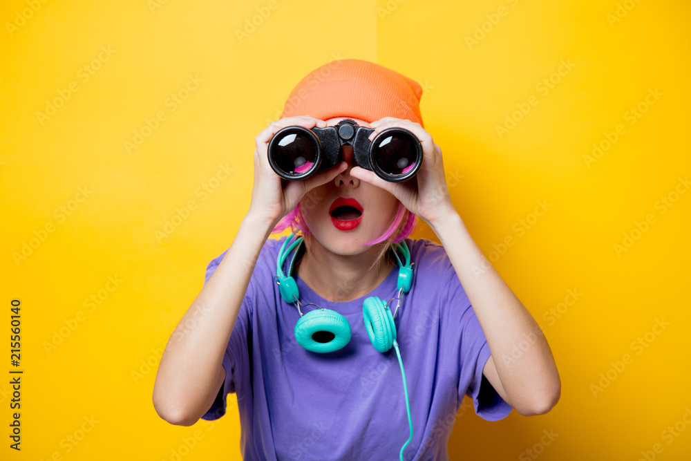 Young style girl in purple clothes with binoculars on yellow background. Clothes in 1980s style Young style girl in purple clothes with binoculars on yellow background. Clothes in 1980s style