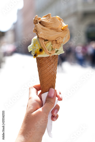 melting delicious ice cream in waffle cone gelato pistachio salty caramel holding female hand