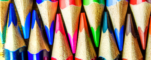 multicolored pencils on wooden background forming a pattern with copy space
