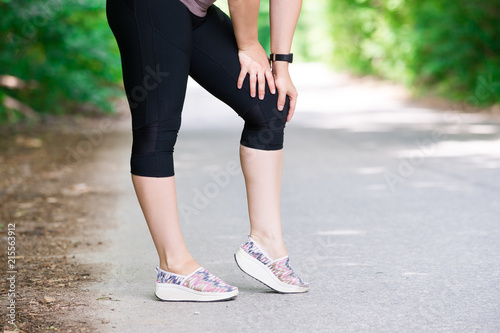 Pain in woman's knee, massage of female leg, injury while running, trauma during workout © staras