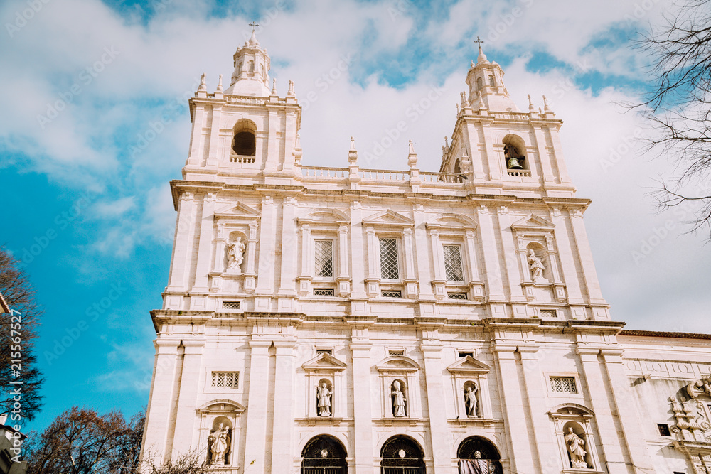 Obraz premium Facade of Monastery of Sao Vicente de Fora in Alfama, Lisbon against blue sky with white clouds. The monastery contains the royal pantheon of the Braganza monarchs of Portugal