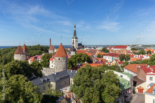 City walls' and St. Olaf's (or Olav's) church's towers and other buildings at the Old Town in Tallinn, Estonia, viewed from above on a sunny day in the summer.