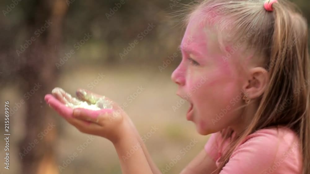 The girl blows off colored powders from her hands. Holi Festival The girl blows off colored powders from her hands. Holi Festival