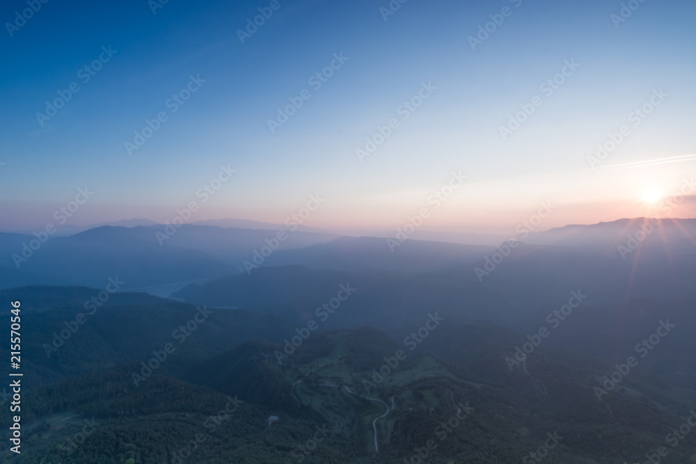 Fototapeta premium Sunset panorama of successive mountains sun bathed close to sunset time without clouds but some tiny sun rays at Catalonia, Spain