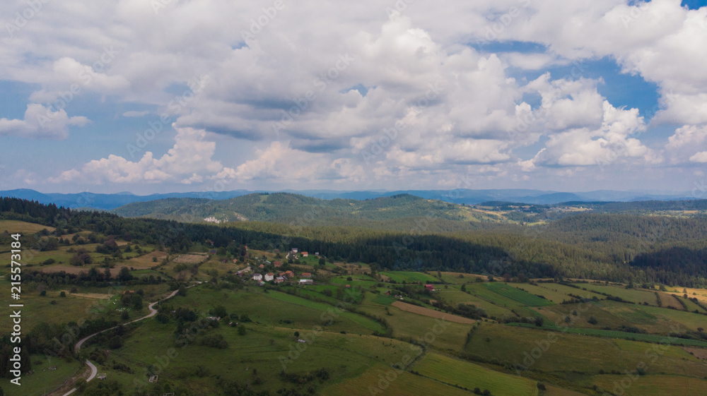aerial view on forest and fields and small village in distance 