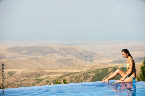 Relaxing woman in luxury hotel pool on holidays vacation travel. Young female person enjoying in infinity pool spa at hotel resort in an exotic paradise getaway.