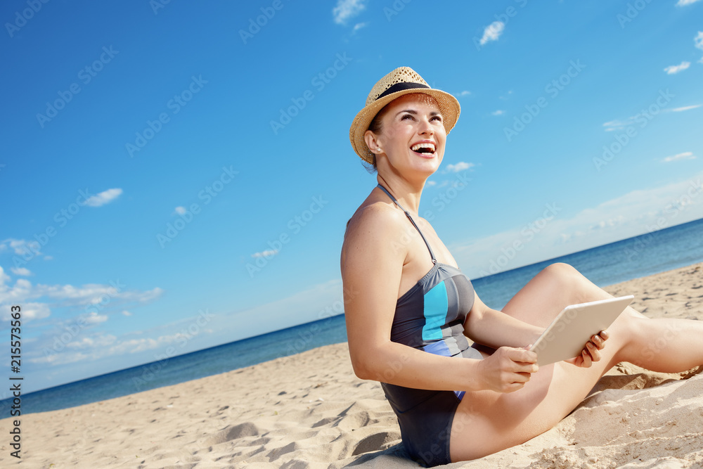 happy woman with tablet PC looking into distance on seacoast