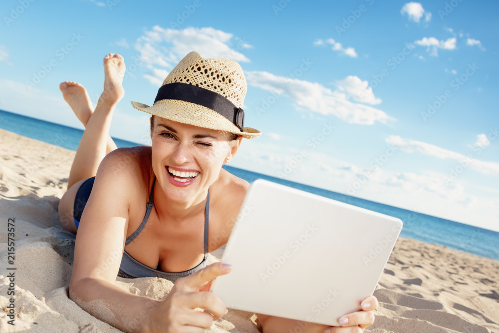 Fototapeta premium smiling modern woman in beachwear with tablet PC on seashore