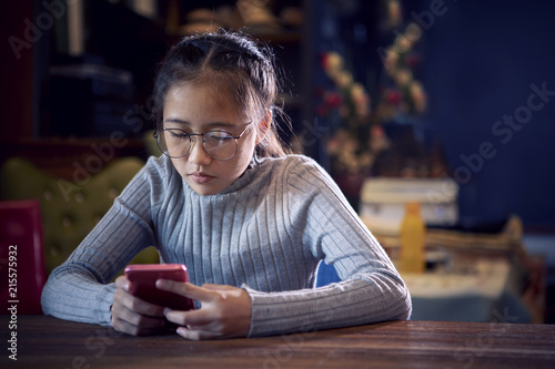 face of asian teenager reading message on smart phone in home living room