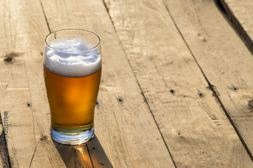 Szklanka piwa na drewnianym blacie.