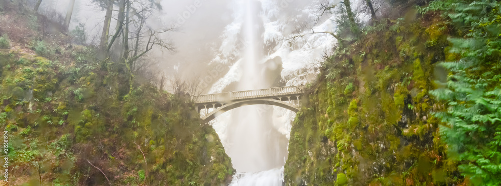Fototapeta premium Panorama icy Multnomah Falls in winter time. It is a waterfall on the Oregon side of the Columbia River Gorge, along the Historic Columbia River Highway. Natural and seasonal waterfall background