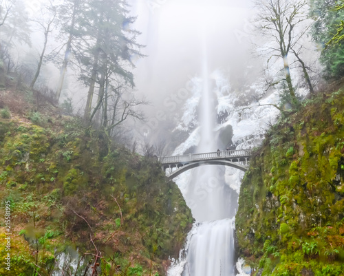 Beautiful icy Multnomah Falls in winter time. It is a waterfall on the Oregon side of the Columbia River Gorge, along the Historic Columbia River Highway. Natural and seasonal waterfall background photo