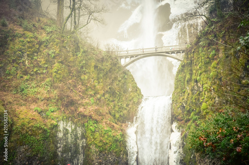 Vintage tone beautiful pedestrian stone bridge and knee-wobbling vantage point over the second tier 69-foot drop of Multnomah Falls lower in winter time. Natural and seasonal waterfall background photo