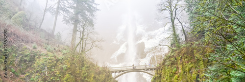 Panorama icy Multnomah Falls in winter time. It is a waterfall on the Oregon side of the Columbia River Gorge, along the Historic Columbia River Highway. Natural and seasonal waterfall background photo