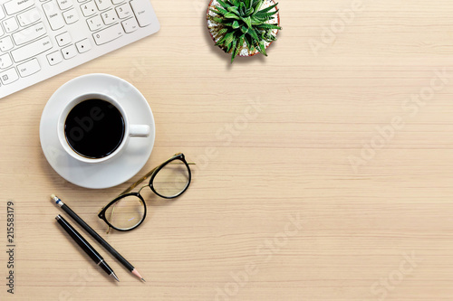 Top view of Office desk with keyboard, hot coffee, plant, vintage eyeglasses on top view and copy space. Business desk minimal style concept with copy space.