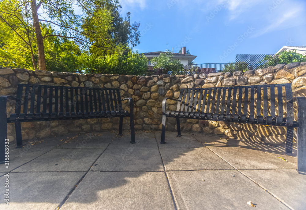 Pair of benches on a walkway with stone wall