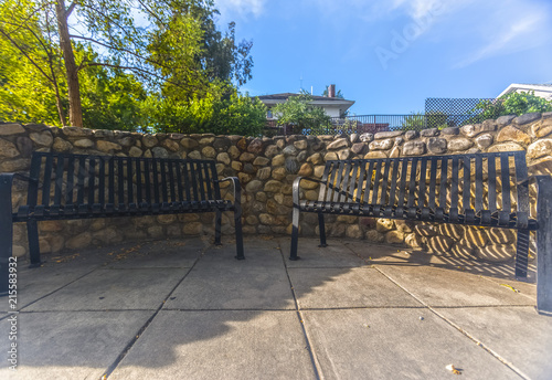 Pair of benches on a walkway with stone wall © Jason