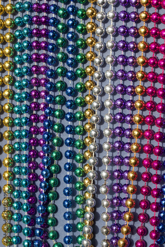 Multi-color Mardi Gras beads in rows on neutral blue background