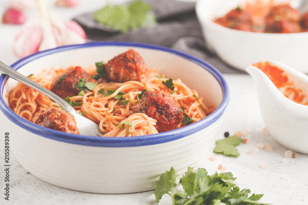 Pasta with meatballs in tomato sauce with parsley and garlic in white dish, white background. Pasta with meatballs in tomato sauce with parsley and garlic in white dish, white background.