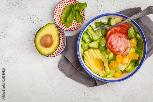 Green zucchini noodles salad with tomatoes, avocado and basil. Healthy vegan zucchini pasta.