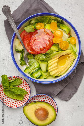 Green zucchini noodles salad with tomatoes, avocado and basil. Healthy vegan zucchini pasta.