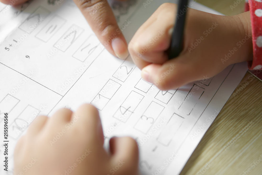 hand of children or student holding pencil and study with learning writing number and math on paper book with teacher or mother point for teach in classroom at school or kindergarten and nursery hand of children or student holding pencil and study with learning writing number and math on paper book with teacher or mother point for teach in classroom at school or kindergarten and nursery