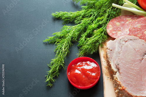 salamis, tomato and tomato sauce, greens and green onionon black background with copyspace photo