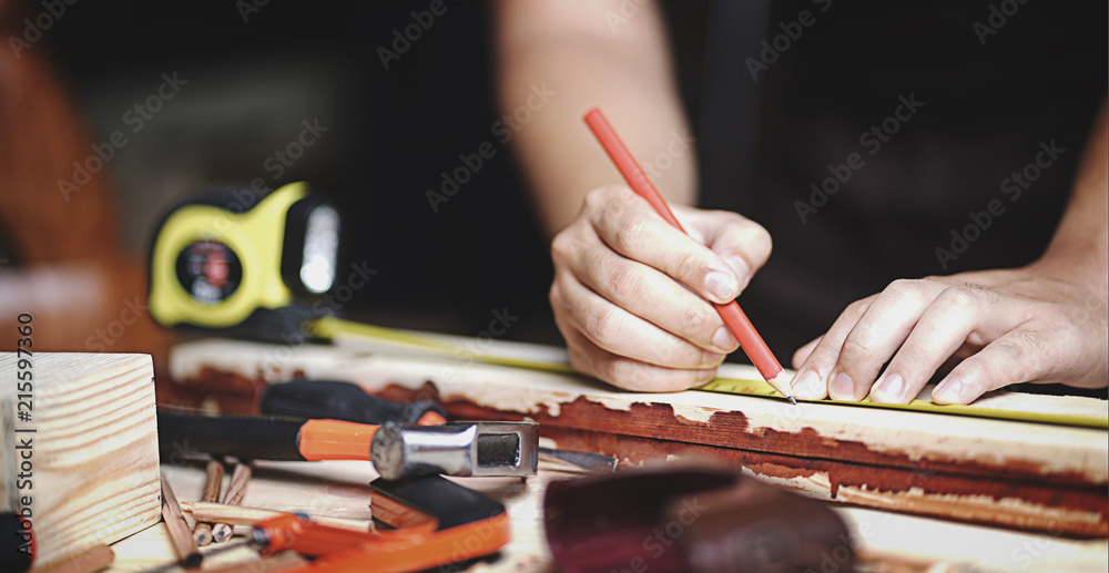 Close up Carpenter Working in Woodworking Workshop. Making Line with Ruler and Pencil on Planks of Wood Close up Carpenter Working in Woodworking Workshop. Making Line with Ruler and Pencil on Planks of Wood