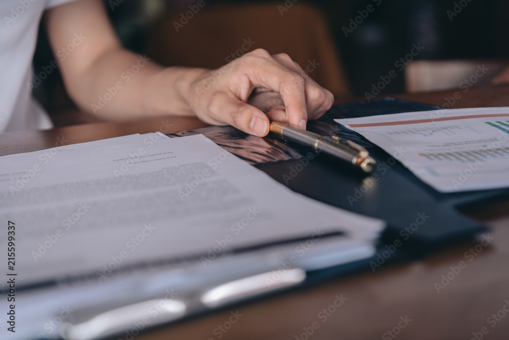 Businesswomen writing signed agreements on official documents to the company's profits. Which is filled with documents and concept for the cooperation of its partners. Businesswomen writing signed agreements on official documents to the company's profits. Which is filled with documents and concept for the cooperation of its partners.