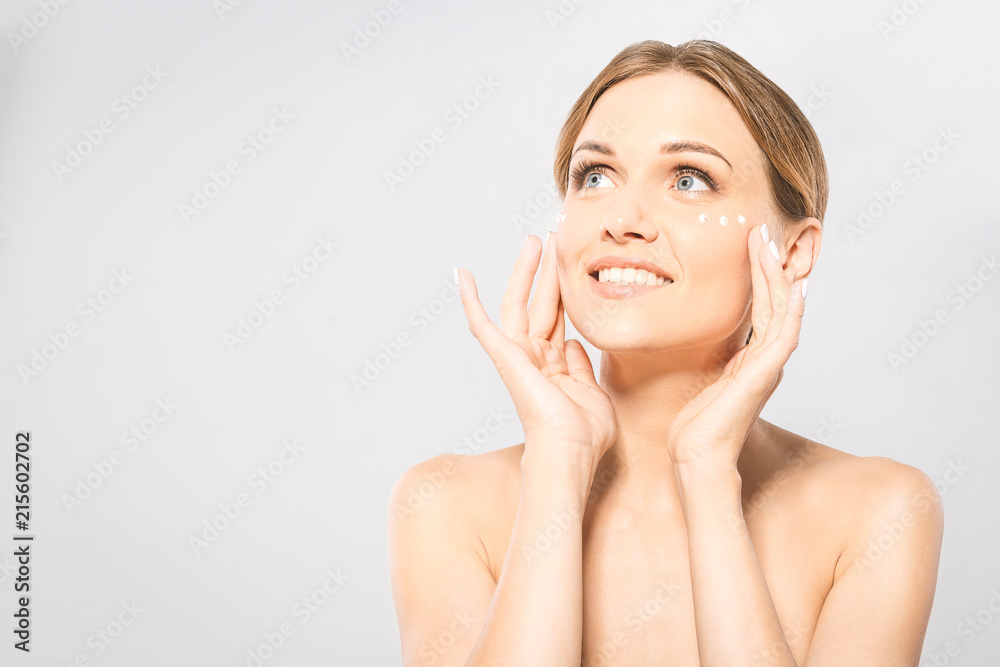 Portrait of young beautiful woman smiling while taking some facial cream isolated on white background with copy space. Portrait of young beautiful woman smiling while taking some facial cream isolated on white background with copy space.