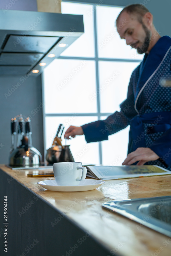 Fototapeta premium A cup of coffee on the background of a man who cooks coffee on the stove
