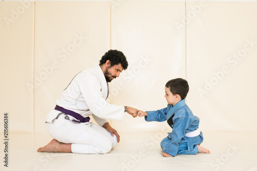 Fotografie Male karate instructor training little child in dojo or jiu-jitsu at gym at tatami