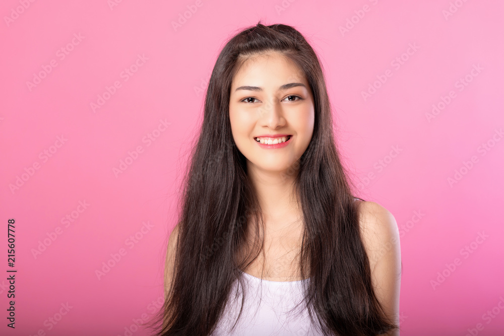 Portrait of a smiling attractive woman in white tanktop outfit posing while standing and smiling at camera isolated over pink background. Portrait of a smiling attractive woman in white tanktop outfit posing while standing and smiling at camera isolated over pink background.