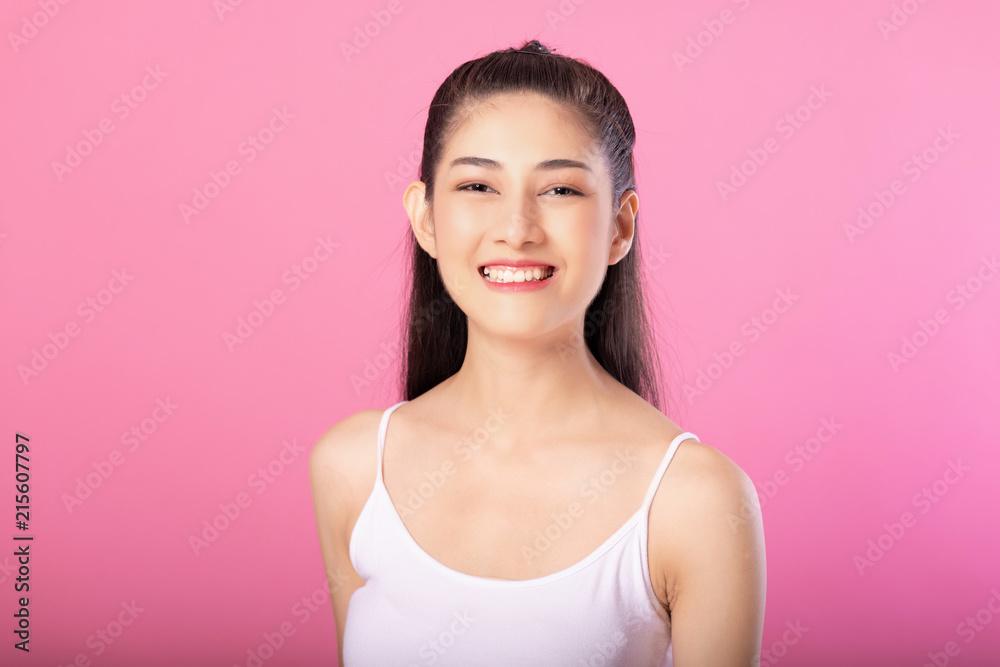 Portrait of a smiling attractive woman in white tanktop outfit posing while standing and smiling at camera isolated over pink background. Portrait of a smiling attractive woman in white tanktop outfit posing while standing and smiling at camera isolated over pink background.