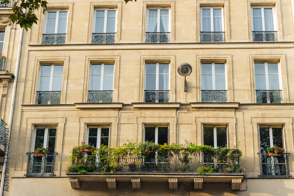 Old Paris residential buildings with balconies and flowers. Beautiful facade of typical french city house. Background. European architecture and city life, lifestyle and expensive real estate concept Old Paris residential buildings with balconies and flowers. Beautiful facade of typical french city house. Background. European architecture and city life, lifestyle and expensive real estate concept