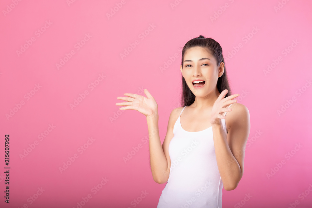 Portrait of a smiling attractive woman in white tanktop outfit with surprise pose while standing and smiling at camera isolated over pink background. Portrait of a smiling attractive woman in white tanktop outfit with surprise pose while standing and smiling at camera isolated over pink background.