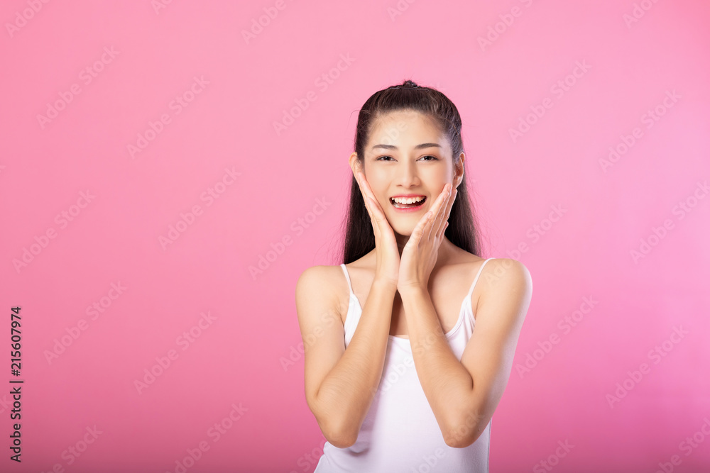 Portrait of a smiling attractive woman in white tanktop outfit with surprise pose while standing and smiling at camera isolated over pink background. Portrait of a smiling attractive woman in white tanktop outfit with surprise pose while standing and smiling at camera isolated over pink background.
