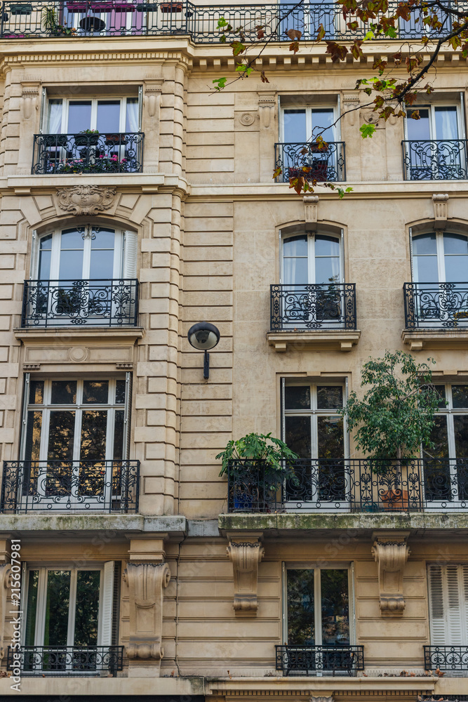 Old Paris residential buildings with balconies and flowers. Beautiful facade of typical french city house. Background. European architecture and city life, lifestyle and expensive real estate concept