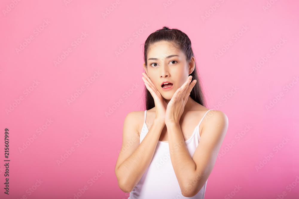 Portrait of a smiling attractive woman in white tanktop outfit with surprise pose while standing and smiling at camera isolated over pink background. Portrait of a smiling attractive woman in white tanktop outfit with surprise pose while standing and smiling at camera isolated over pink background.