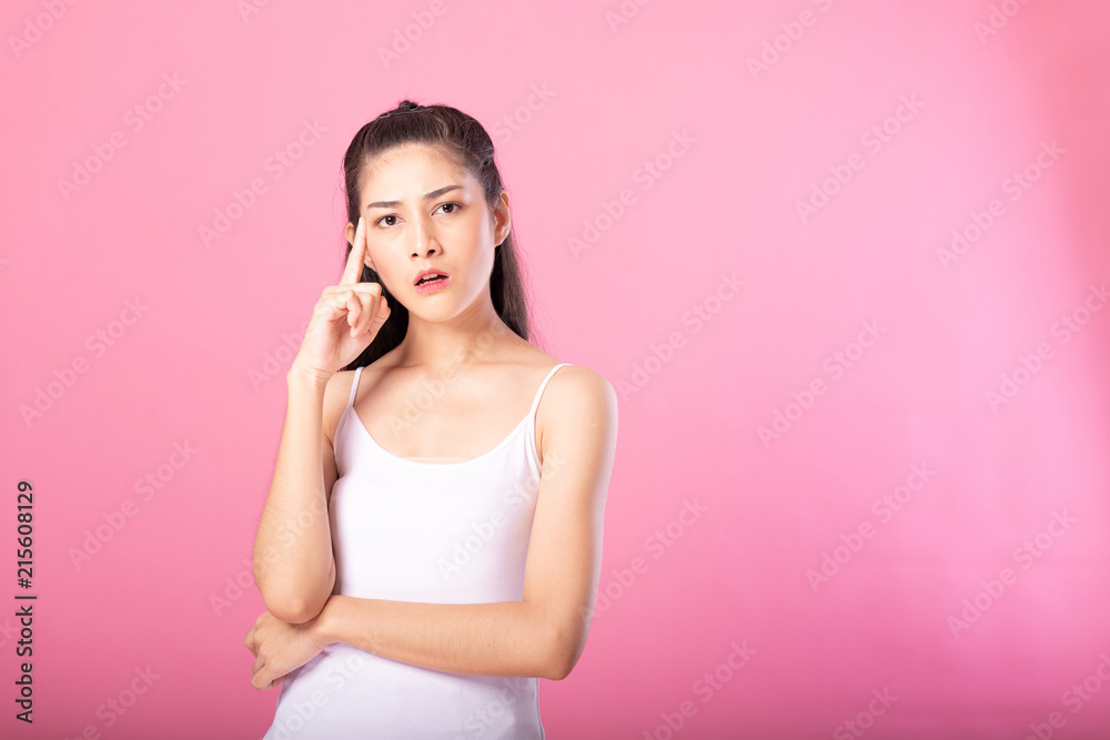 Portrait of a smiling attractive woman in white tanktop outfit with thinking pose while standing and smiling at camera isolated over pink background. Portrait of a smiling attractive woman in white tanktop outfit with thinking pose while standing and smiling at camera isolated over pink background.